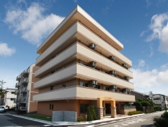 5階建てのモダンな介護施設建物。ベージュ系の外壁に開放的なバルコニーが特徴
