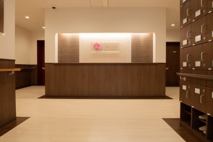 モダンな受付カウンター、照明壁、木製ロッカー配置された施設のロビー